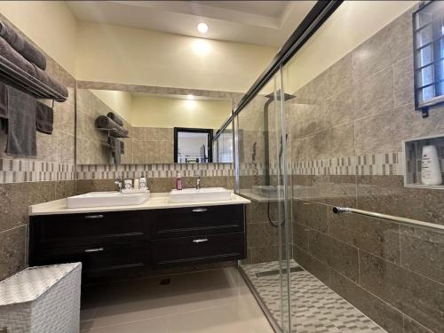 a bathroom with two sinks and a glass shower at Pyramid Point Vacation Stay in Ocho Rios