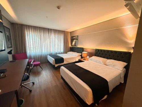 a hotel room with two beds and a desk at Quartos no QS Marista in Goiânia