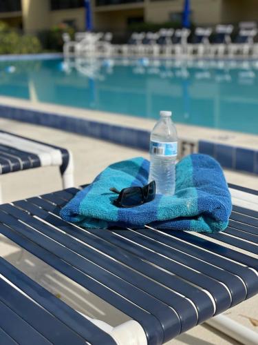 a towel and a bottle of water next to a swimming pool at Pier Pressure Beachfront Wpool in Cocoa Beach