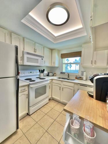 a kitchen with white appliances and a ceiling at Pier Pressure Beachfront Wpool in Cocoa Beach
