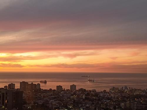 a city skyline with ships in the ocean at sunset at Hostel Agua Santa in Viña del Mar