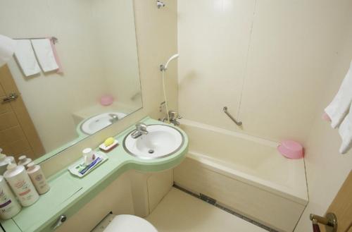 a bathroom with a sink and a toilet and a mirror at Orange Hotel Jeju in Jeju