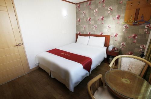 a bedroom with a bed and a table in a room at Orange Hotel Jeju in Jeju
