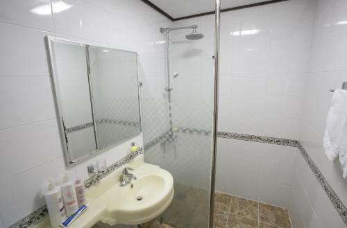 a white bathroom with a sink and a shower at Orange Hotel Jeju in Jeju