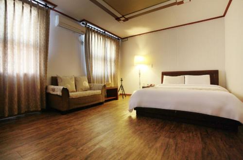 a bedroom with a bed and a chair and a couch at Orange Hotel Jeju in Jeju