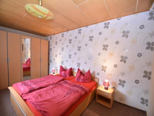 a bedroom with a bed with pink sheets and flowers on the wall at Ferienhaus in Cattenstedt Harz mit Garten in Cattenstedt