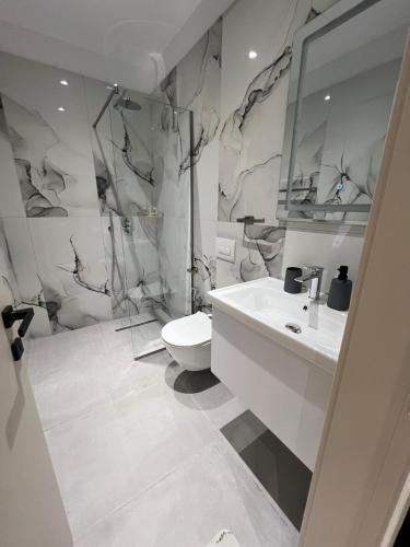 a white bathroom with a toilet and a sink at Vila Serenita in Vlorë