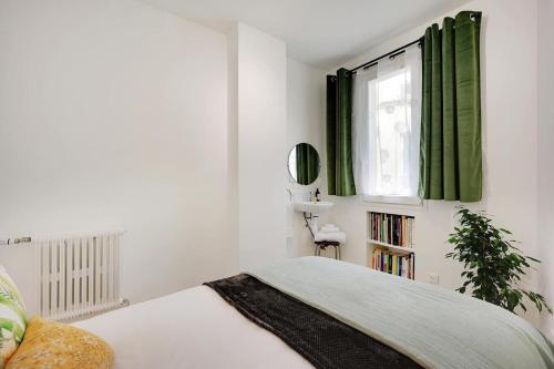 - une chambre avec un lit et une fenêtre avec des rideaux verts dans l'établissement Fully Renovated Apartment In Montmartre, à Paris