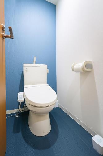 a bathroom with a white toilet in a blue wall at willcourt in Tokyo
