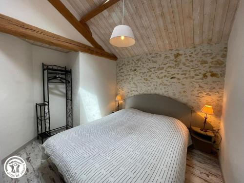 sypialnia z białym łóżkiem i kamienną ścianą w obiekcie Maison plain-pied au cœur du Marais breton, proche plages et Ile d'Yeu - FR-1-426-589 w mieście Le Perrier
