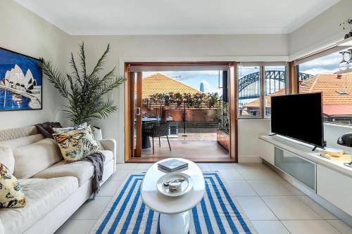 a living room with a couch and a tv at Heatherbrae II - Stunning Harbour Bridge Views! in Sydney