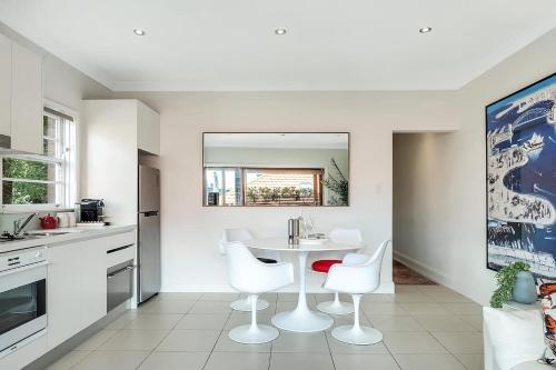 a kitchen with a white table and white chairs at Heatherbrae II - Stunning Harbour Bridge Views! in Sydney