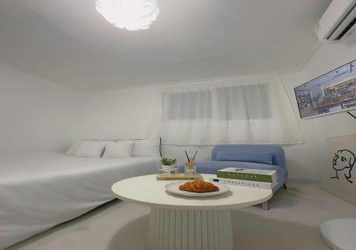 a white bedroom with a bed and a table with a plate of food at 정담 신도림역 투룸 무료주차 in Seoul
