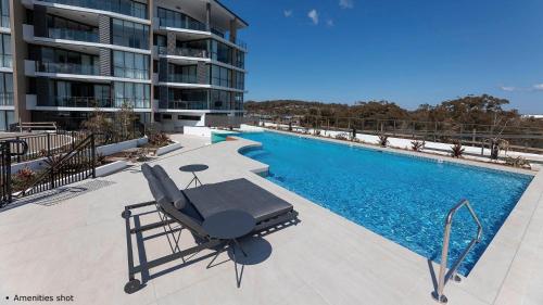 a swimming pool with a chaise lounge next to a building at Solaris 412 in Forster