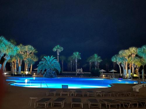 a swimming pool with chairs and palm trees at night at Silver Shells in Destin