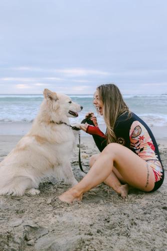 a woman sitting on the beach with a dog at Luxe Ob Retreat Sauna, Bikes & Beach Nearby in San Diego
