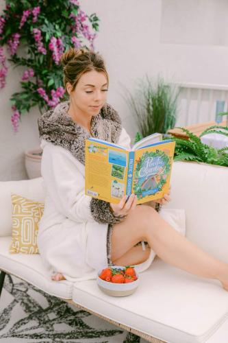 a woman sitting on a bench reading a book at Luxe Ob Retreat Sauna, Bikes & Beach Nearby in San Diego