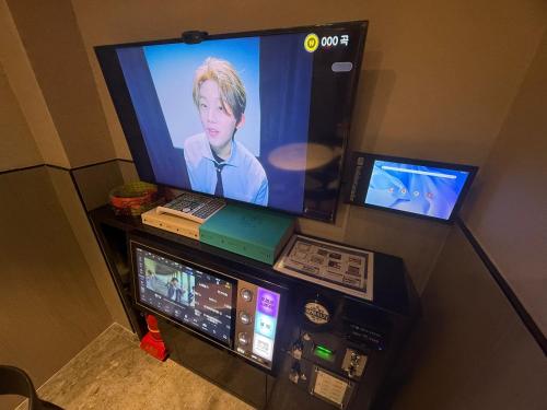 a television with a laptop and two monitors on a stand at Hotel tt Gupo in Busan
