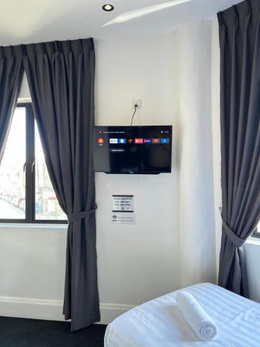 a bedroom with a bed and a television on the wall at Quee Hotel in George Town