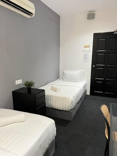 a room with two beds and a black door at Quee Hotel in George Town