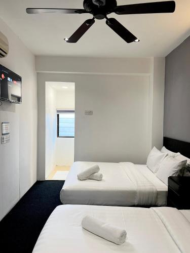 two beds in a room with a ceiling fan at Quee Hotel in George Town