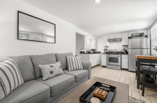 a living room with a gray couch and a kitchen at Little Hyde Out - Updated Hyde Park 1st Floor Apartment in Tampa