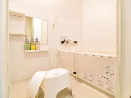 a white bathroom with a toilet and a sink at Alphabed広島平和大通り in Hiroshima