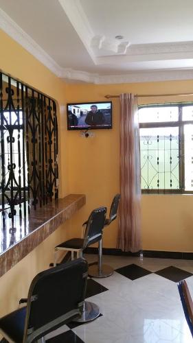 una sala de espera con 2 sillas y TV de pantalla plana en Mauya Executive Lodge, en Dar es Salaam