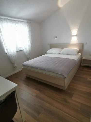 a white bedroom with a bed and two windows at Apartments Golub in Cesarica