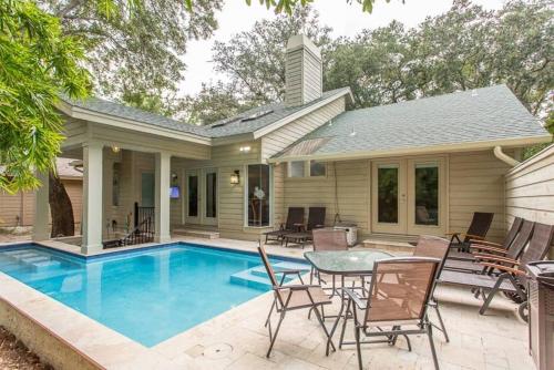 eine Terrasse mit Tisch und Stühlen neben einem Pool in der Unterkunft Luxe Stay W Heated Pool, Swim-up Bar & Hot Tub in Hilton Head Island
