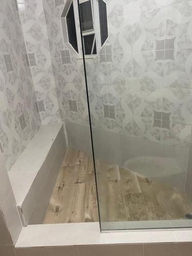 a glass shower in a bathroom with a wooden floor at Marshan villa in Montego Bay
