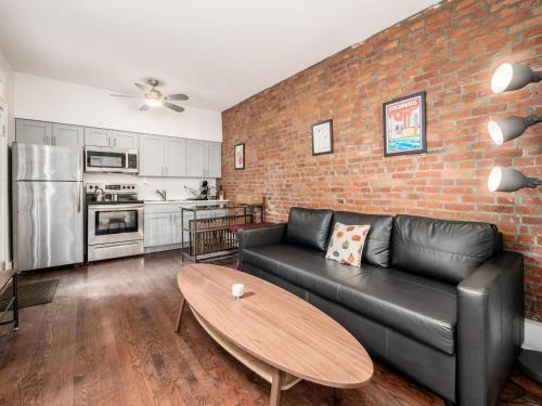 a living room with a black couch and a brick wall at Cute German Village LilHausCity ParkPetsOK in Columbus