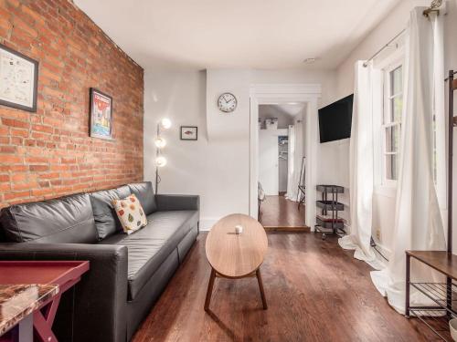 a living room with a couch and a brick wall at Cute German Village LilHausCity ParkPetsOK in Columbus