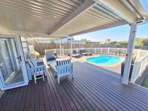 a wooden deck with chairs and a swimming pool at Seagulls Beach House in Port Shepstone
