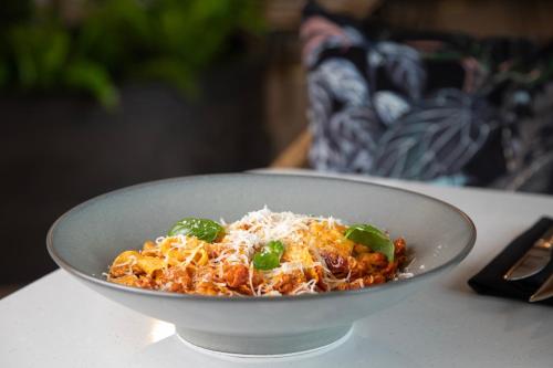 a bowl of pasta with cheese and green peppers on a table at The Clements Hotel in Cambridge