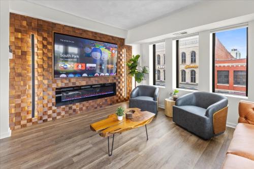 a living room with a flat screen tv on a brick wall at Modern Flat off Meridian - Walk Anywhere Downtown in Indianapolis