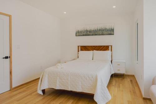 a white bed in a white bedroom with a wooden floor at Lux 3BD Minutes Walk to Airport in Boston