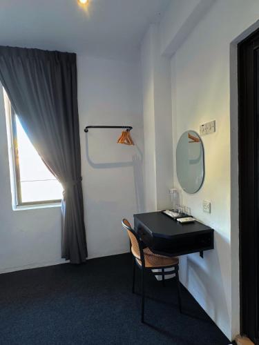 a room with a table with a mirror and a chair at Quee Hotel in George Town