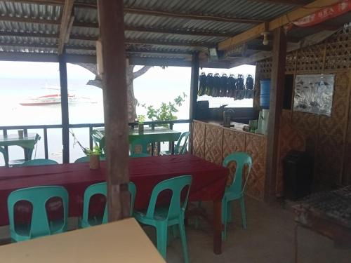 a table and chairs in a restaurant with a view of the water at Enas cottages in Pamilacan IsLand in Baclayon