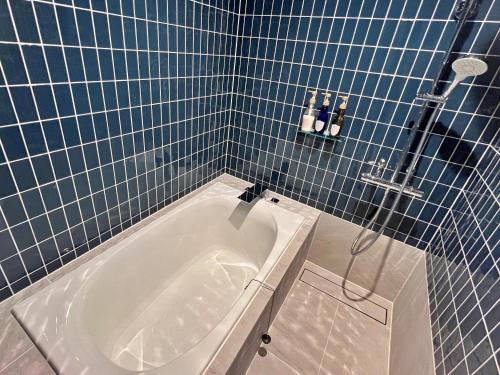 a bathroom with a tub in a blue tiled bathroom at The 曜 Terrace in Hirado