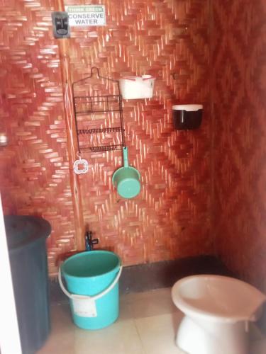 a bathroom with a toilet and a green bucket at Enas cottages in Pamilacan IsLand in Baclayon