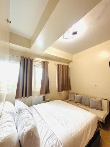 a bedroom with a large bed and a window at 11 Poolside Balcony Bliss in Iloilo City