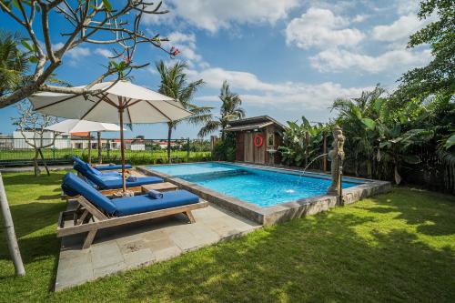 a swimming pool with two blue lounge chairs and an umbrella at Paddy's Glamping Managed by Manara in Canggu