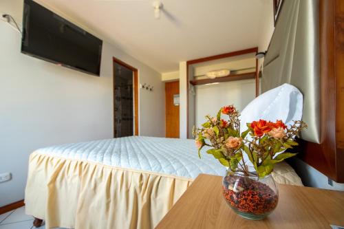 a bedroom with a bed and a vase of flowers on a table at Ssamana María Apartment & Guesthouse in Arequipa