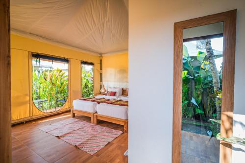 a bedroom with a bed and a large window at Paddy's Glamping Managed by Manara in Canggu