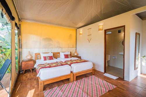 a bedroom with two beds and a rug at Paddy's Glamping Managed by Manara in Canggu