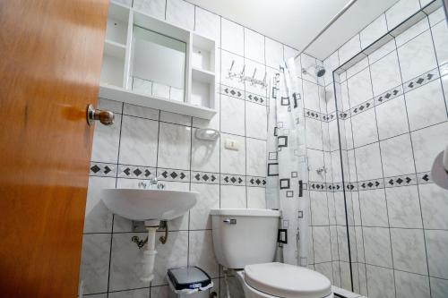a white bathroom with a toilet and a sink at Ssamana María Apartment & Guesthouse in Arequipa