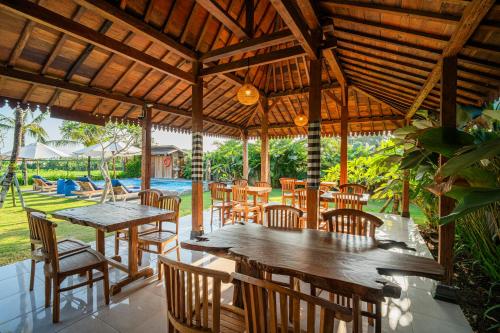 a restaurant with wooden tables and chairs and a pool at Paddy's Glamping Managed by Manara in Canggu