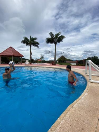 two men in the swimming pool at a resort at Wasi loma casa campestre in Pedro Vicente Maldonado