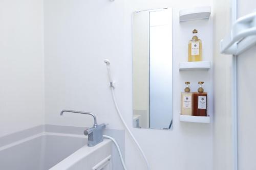 a white bathroom with a mirror and a sink at Shinjuku family apartment in Tokyo